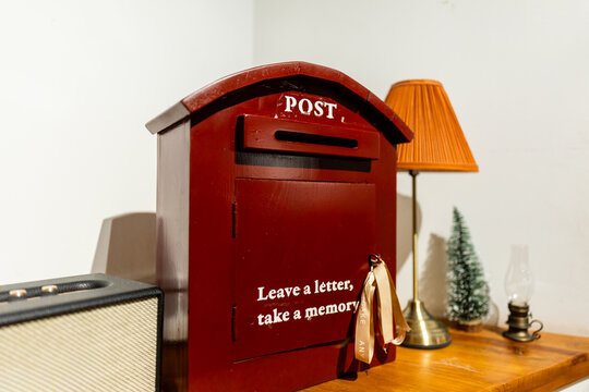 Red wooden postbox in a cafe interior with decorative lamp