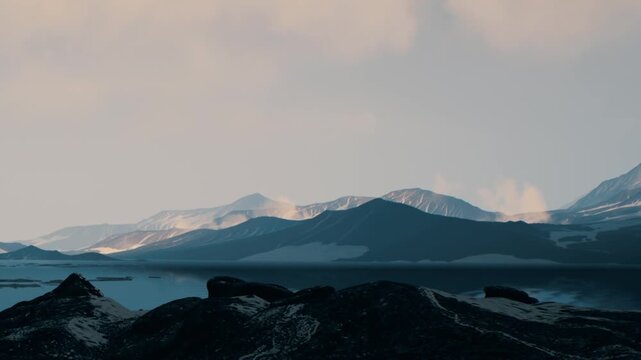 Mountains rise in the background with lakes in the foreground during sunset. The sky has clouds that cover some of the sun, creating soft light over the scene.