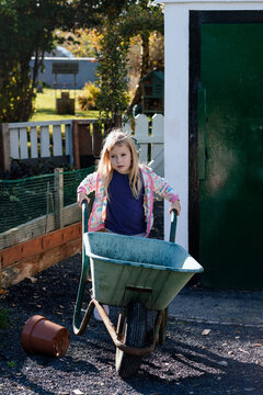 Girl pushing a wheelbarrow in allotment