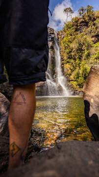 Cachoeiras dos Garcias, Minas Gerais - Detalhe da perna de um homem em p&eacute;, pr&oacute;ximo de uma cachoeira de &aacute;guas cristalinas 