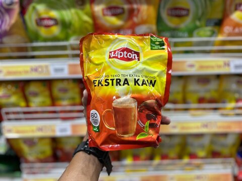 Sabah, Malaysia - September 02, 2026 : Hand holding Lipton tea products in pouch and box packaging in store shelf context.