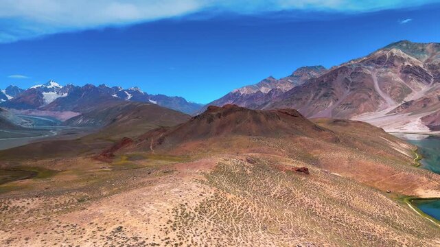 Cinematic Drone View of the Rugged Himalayan Mountains Surrounding Chandratal Lake with Rocky Slopes, Snowy Peaks and Dramatic Spiti Valley Wilderness