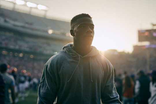 Determined Male Athlete Walking in Stadium at Sunset