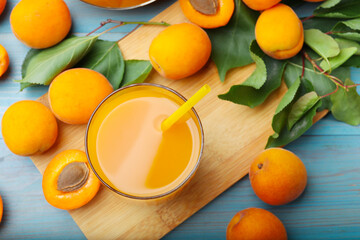 Apricot juice in glass, fresh fruits and leaves on light blue wooden table, flat lay © New Africa