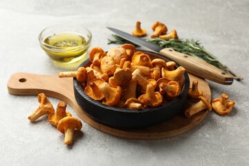 Chanterelle mushrooms, knife, oil and rosemary on grey table, closeup © New Africa