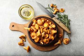 Chanterelle mushrooms, knife, oil and rosemary on grey table, flat lay © New Africa