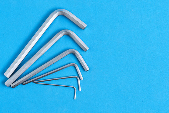 Set L shaped Allen keys arranged in fan shape on blue background with generous copy space.