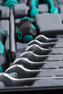 Selective focus close up on open end spanners and screwdriver tip inside grey plastic toolbox.