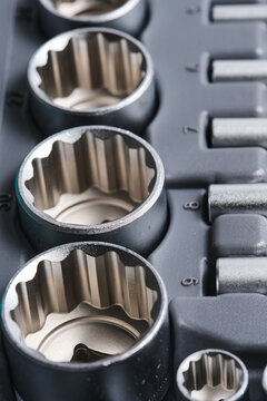 Close up top view metal socket wrench heads neatly aligned in hard plastic tool case tray.