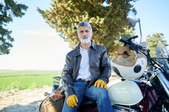 Confident mature biker sitting on his motorcycle enjoying the view of nature