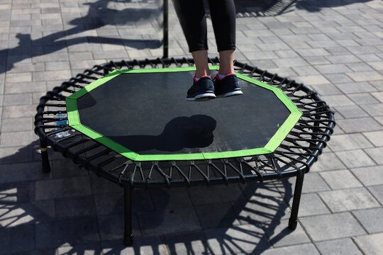 Woman jumping on small fitness trampoline outdoor workout exercise session