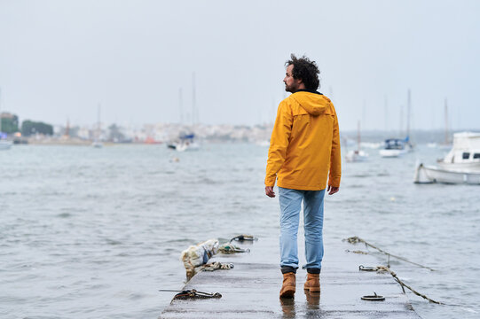 Lonely sailor walking on a pier in a rainy day at the seaport