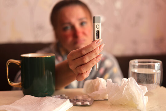 Sick woman showing digital thermometer with high fever cold and flu illness concept