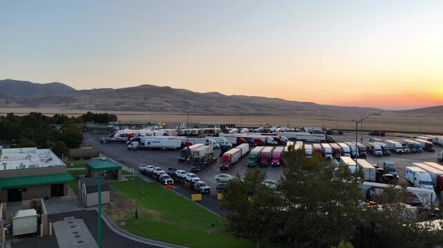 Aerial view of highway truck stop and parked semi trucks at sunset