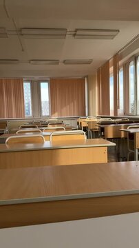 Vertical video of empty classroom with rows of wooden desks and chairs, school study room.