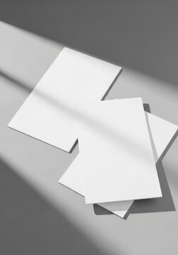 Two empty white paper flyers lying on a neutral surface with soft shadows, creating a professional template for graphic design displays, identity, top, marketing
