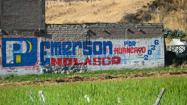 Mantaro Valley, Per&uacute; - July 14, 2026: Political campaign mural promoting a 2026 election in Huancayo. Painted advertising covers a brick wall beside farmland.