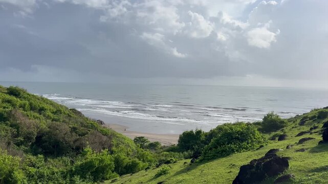 Scenic elevated view of ocean waves washing on sandy coast from green Chapora Fort hill in Goa India