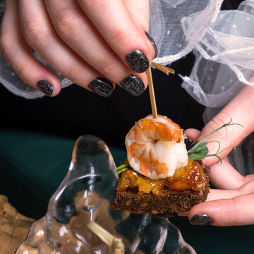 Shrimp and mango chutney canapes in female fingers. Mini sandwich on the party