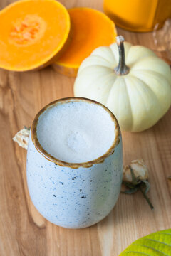 Pumpkin latte with fall leaves and pumpkin on wooden background