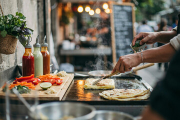 Obraz premium Chef cooking flatbread on griddle at street food market