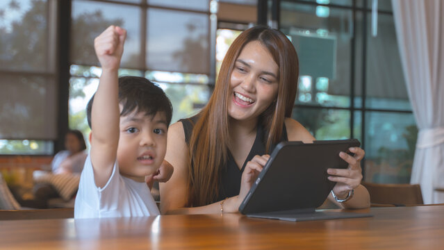 Happy mother and son celebrating success while using a digital tablet together