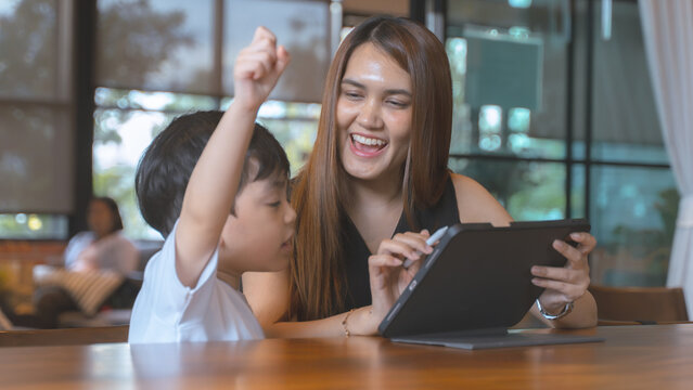 Joyful mother and son celebrating an achievement while using a digital tablet