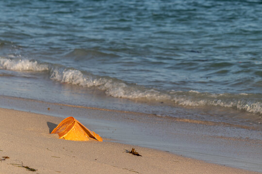 Orange Plastic Bucket Discarded on Beach