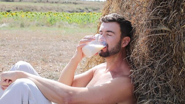 Attractive Shirtless Farmer Drinking Fresh Milk in Sunflower Field