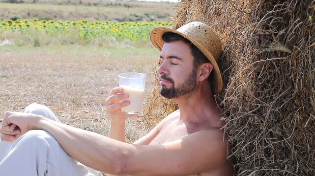 Attractive Shirtless Farmer Drinking Fresh Milk in Sunflower Field