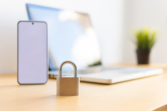 Close up of padlock with smartphone and laptop in background