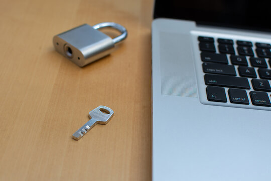 Close up of padlock key with blurred lock and laptop