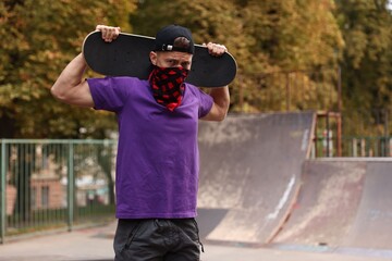 Stylish man with skateboard in skate park. Space for text © New Africa