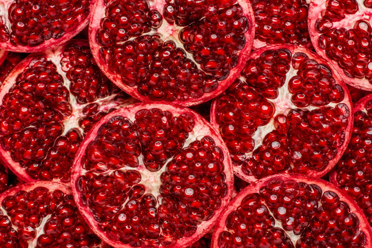 Bright red pomegranate halves with juicy seeds in a full frame view.
