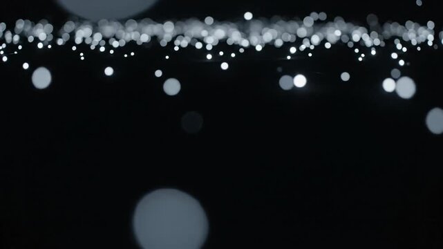 Soft abstract light dots floating calmly on dark background