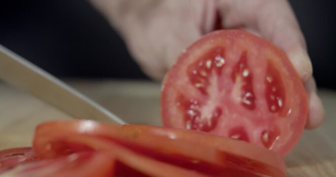 Macro wide close up of knife slicing and chopping a red tomato salad, food,