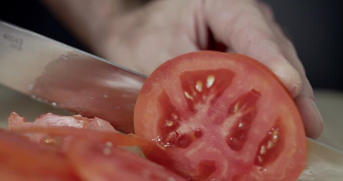 Macro wide close up of knife slicing and chopping a red tomato salad, food,