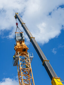 Tower Crane Operator Cab Installation by Mobile Crane with Workers Guiding Assembly High Above Ground
