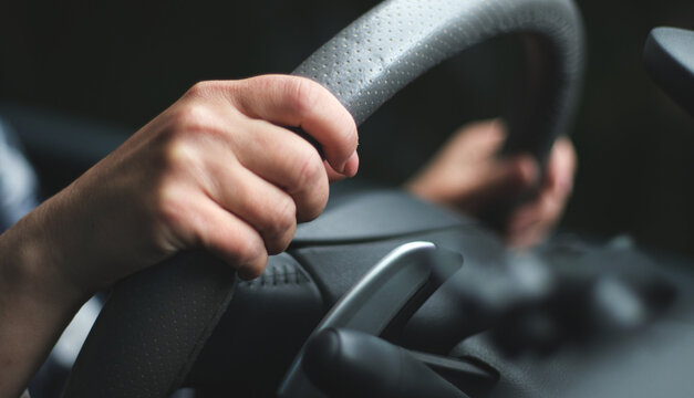 Close-up of woman's hands holding a car steering wheel while driving