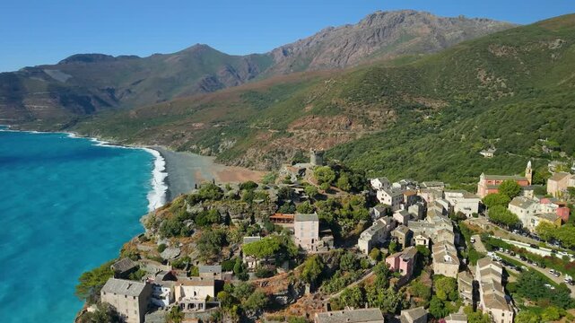 Nonza Cap Corse Corsica France aerial drone flyover perched village black beach turquoise sea waves cliffside historic town sunny morning light mountain backdrop travel destination 4k video