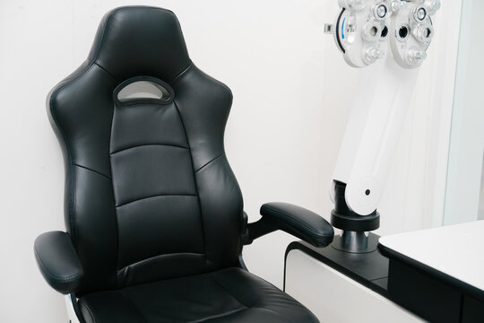 Black leather medical examination chair with professional clinic equipment for peaceful patient eye checkup experience in clinic