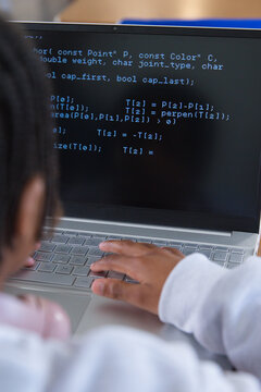 African American youth woman typing code on silver laptop at desk with pink headphones, copy space