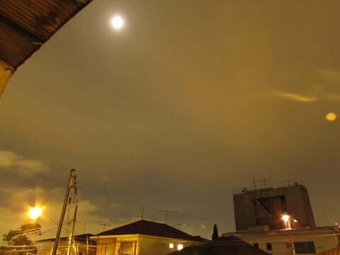 Urban night scene with moonlit sky and illuminated buildings