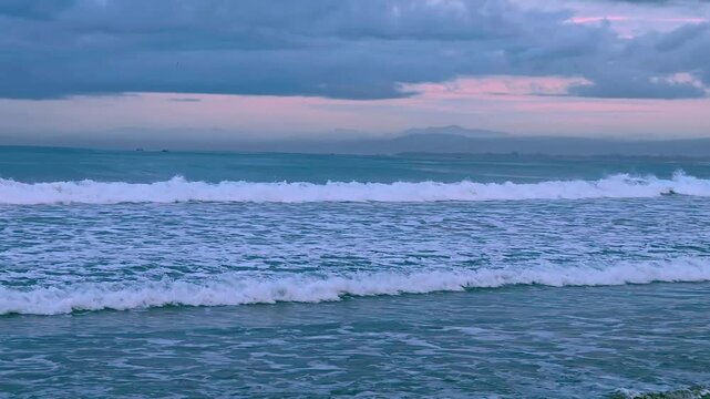 Gentle waves rolling onto the shore of the Indian Ocean at sunset, with warm evening light reflecting across the water and creating a peaceful coastal atmosphere.