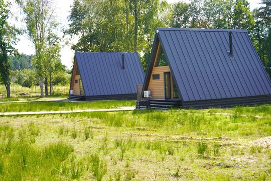 Modern wooden A-frame cabins in a glamping site surrounded by nature. Ideal location for ecotourism, digital detox, peaceful countryside retreat, mental reset, offline relaxation, and serenity