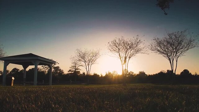 Sunset over serene park with gazebo and trees