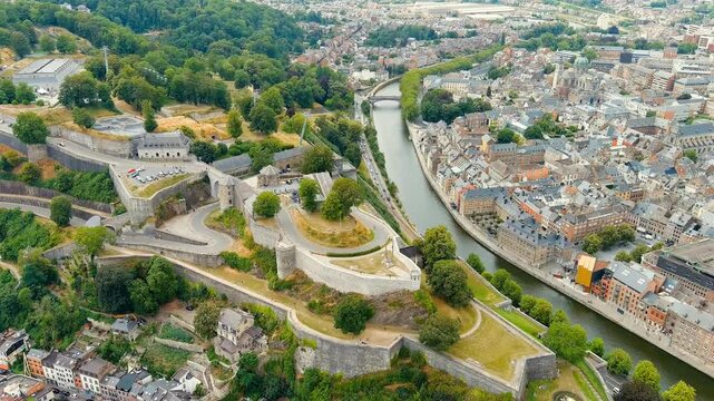Namur, Belgium. Citadelle de Namur - 10th-century fortress with a park, rebuilt several times. Panorama of the central part of the city. River Meuse. Summer day. Drone footage, Departure of the camer