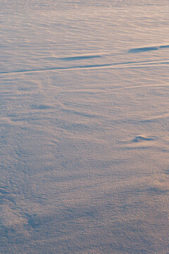 Fresh shiny snow on the ground on a sunny afternoon viewed from above. Abstract winter season background with copy space.