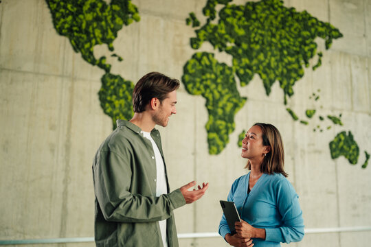 Diverse business professionals discussing global sustainability and green initiatives in modern office environment