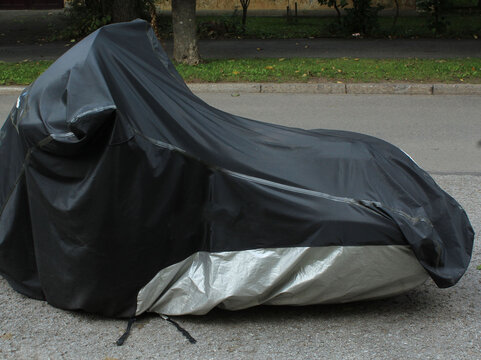 Black Protective Tarp Covering Parked Motorcycle.

